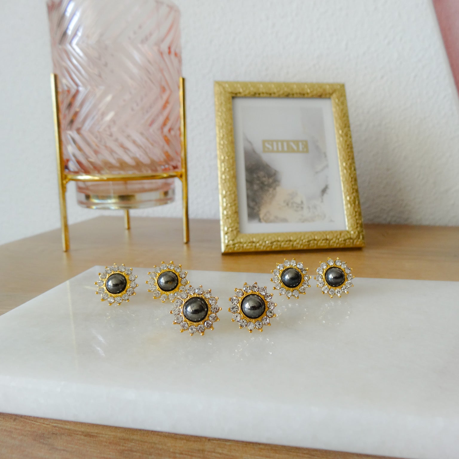 Gouden dames oorknoppen met witte kristal stenen en grijze loodkristal. De gouden dames oorknoppen hebben een bloem motief.