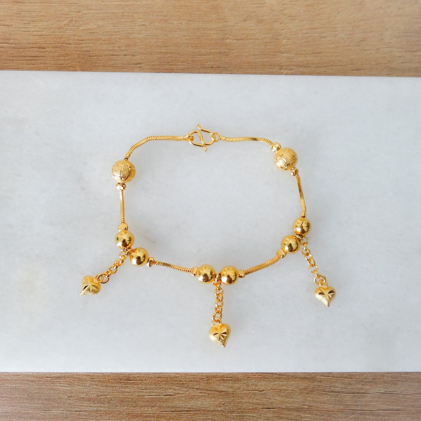 Gouden bedel armbandje met hartjes.