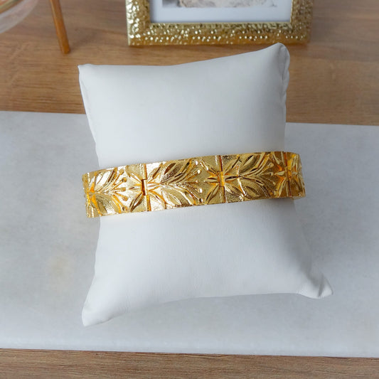 Gouden brede dames armband met een blad en bloem motief.