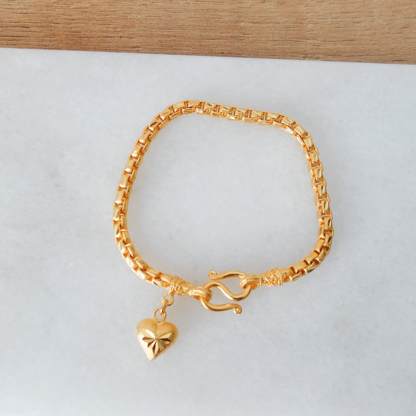 Gouden schakel armband met een bedel hartje.