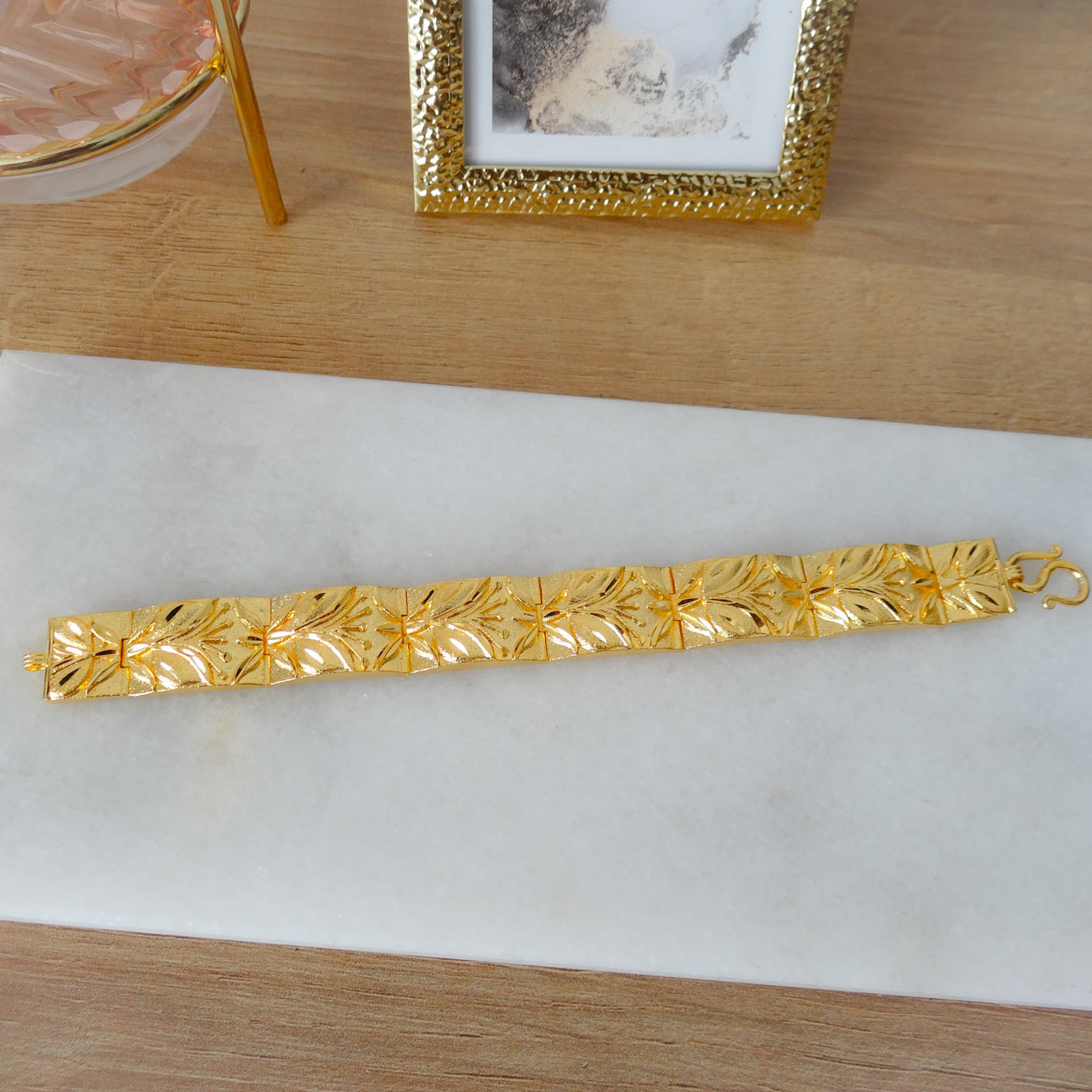 Gouden brede dames armband met een blad en bloem motief.